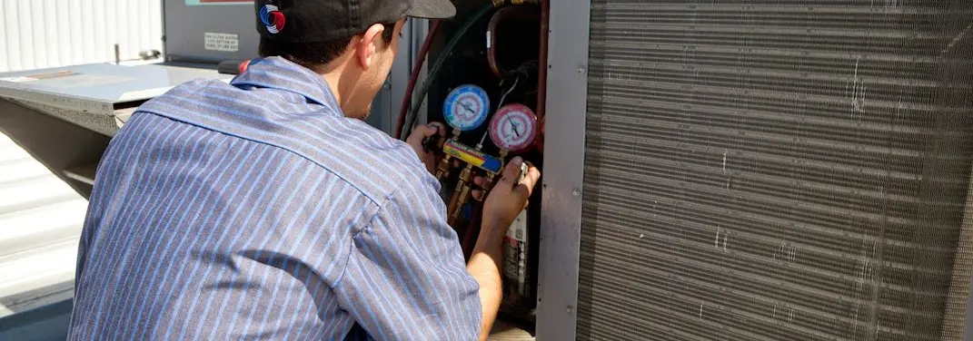 HVAC technician servicing a condenser unit in Dinuba