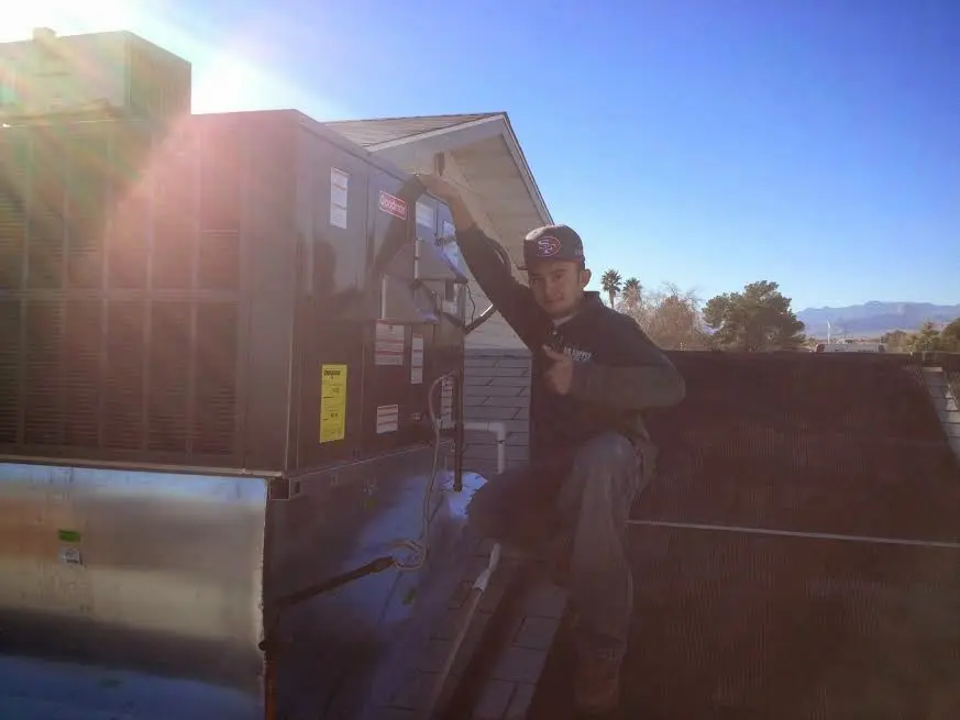 HVAC technician performing HVAC Inspection on a rooftop unit in Dinuba